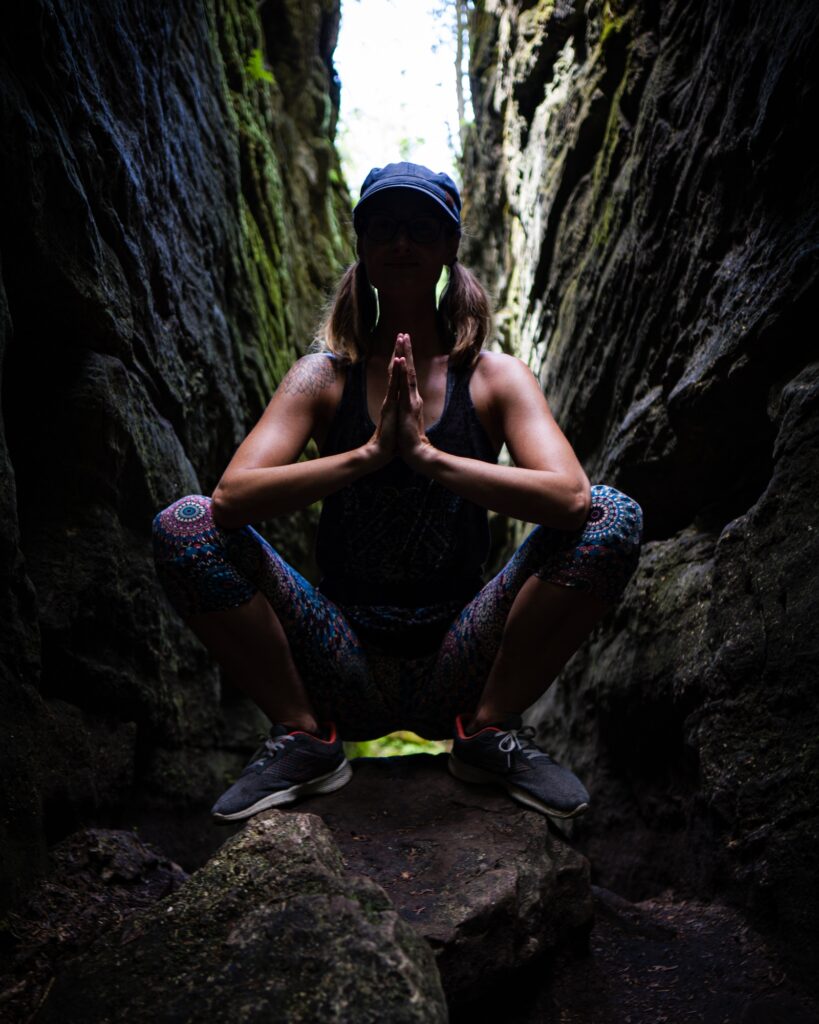 Carole Carter from Living Lotus Online practicing Garland pose on rock formations