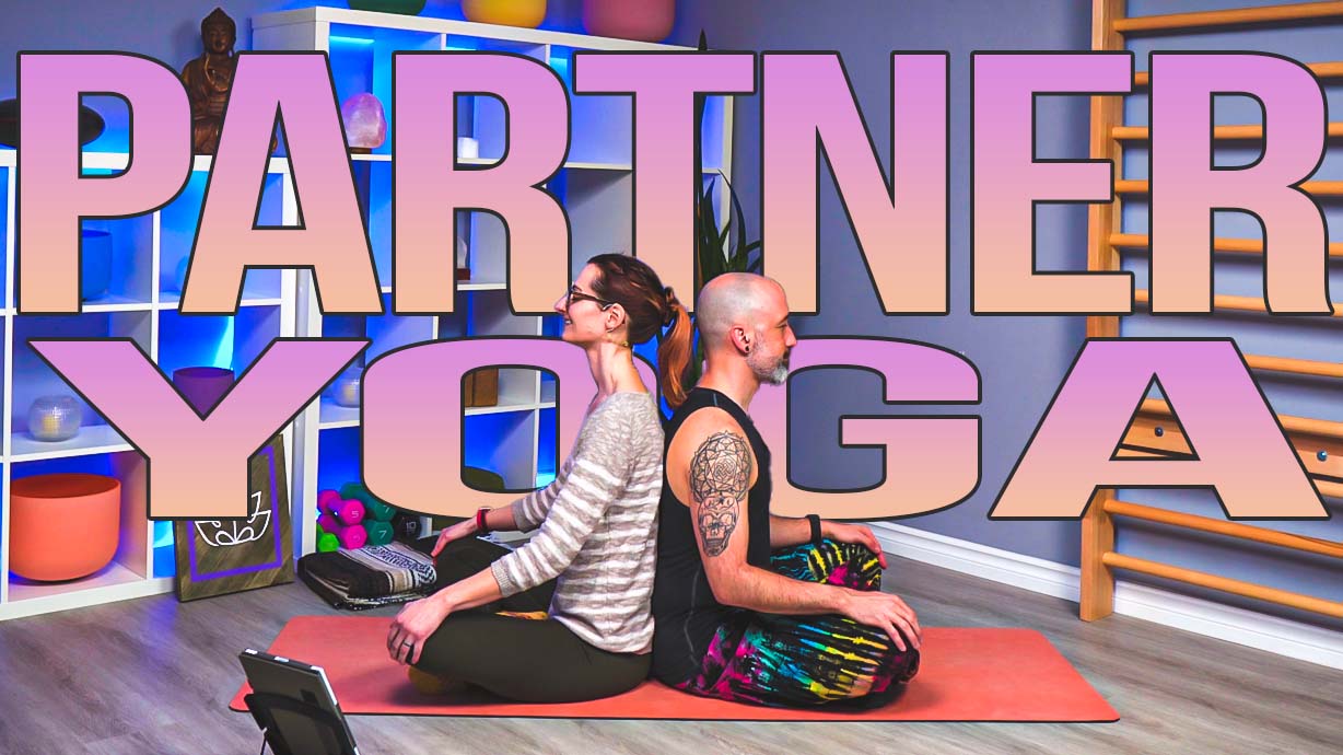 Carole Carter and Paul Mendes from Living Lotus Online sitting back to back on a yoga mat demonstrating partner yoga pose
